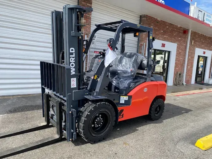 Orange and black WORLD forklift parked outside a building.