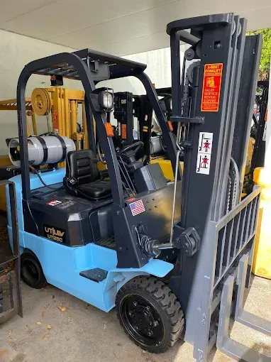 Blue and gray forklift with black wheels parked in an outdoor industrial setting.
