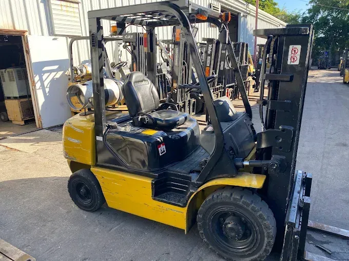 Yellow forklift in an outdoor setting, with black tires and a raised fork.