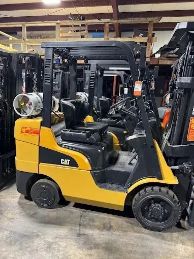 Yellow CAT forklift with black accents parked inside a warehouse.