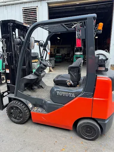 Red and black Toyota forklift outdoors in front of a building.