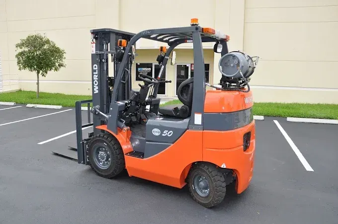 Orange and grey forklift in a parking lot.