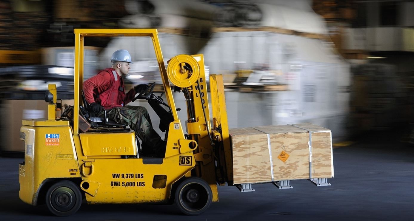 Red forklift carrying cardboard boxes in a warehouse.