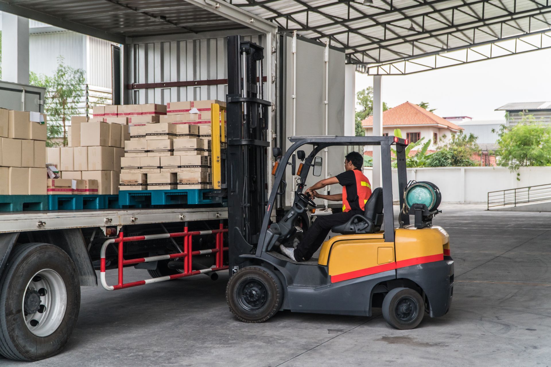 Forklift operator loading boxes onto a truck at a warehouse dock. Forklift operator loading boxes onto a truck at a warehouse dock.