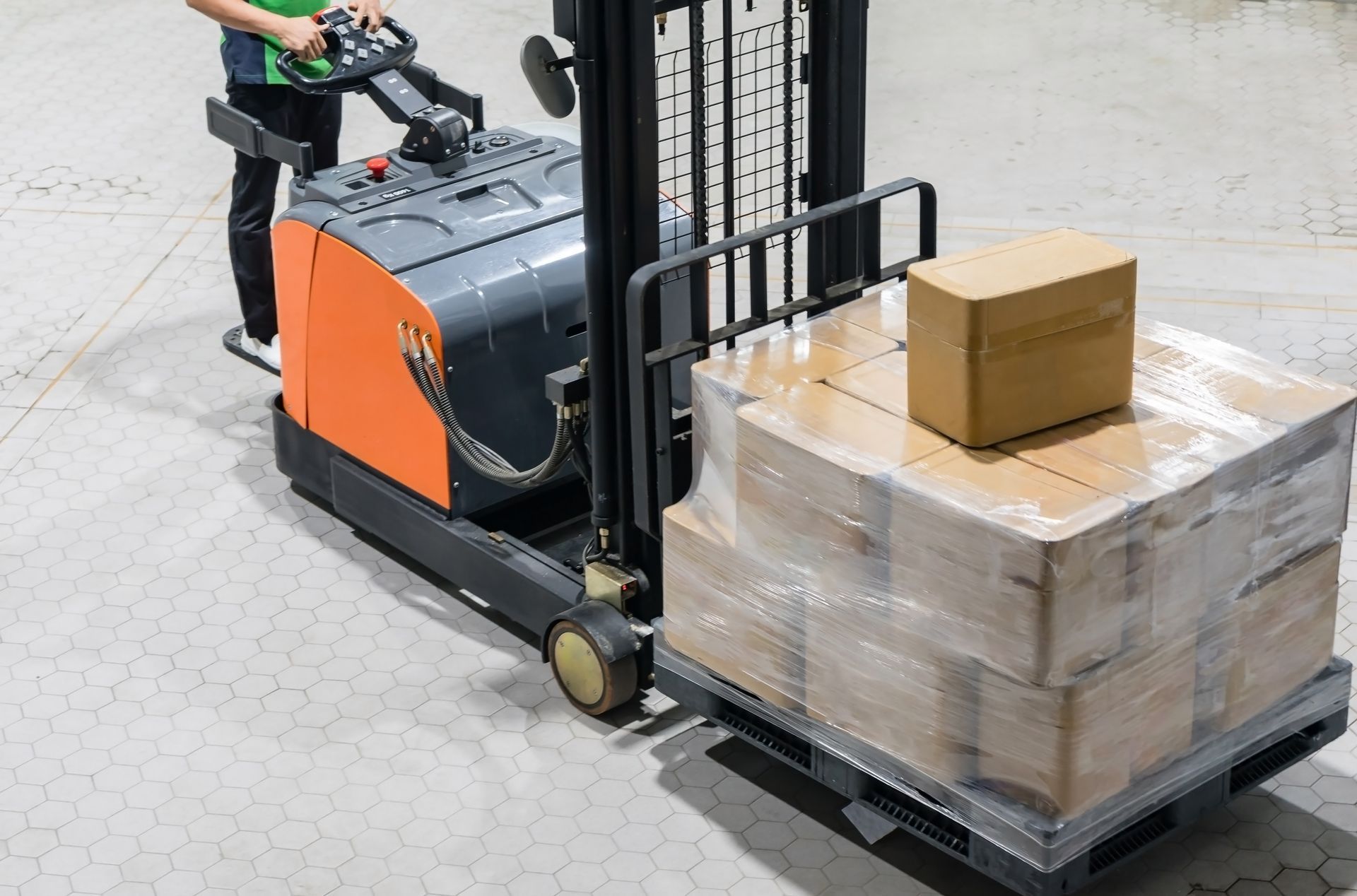 Forklift operator moving wooden pallets in a storage yard under a blue sky.