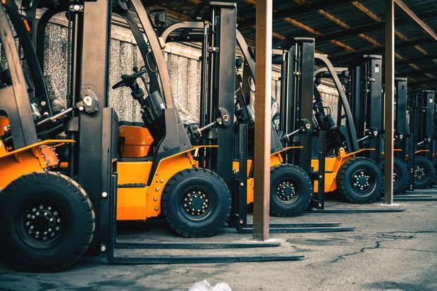 Row of parked yellow and black forklifts under a corrugated metal shelter. Row of parked yellow and black forklifts under a corrugated metal shelter.