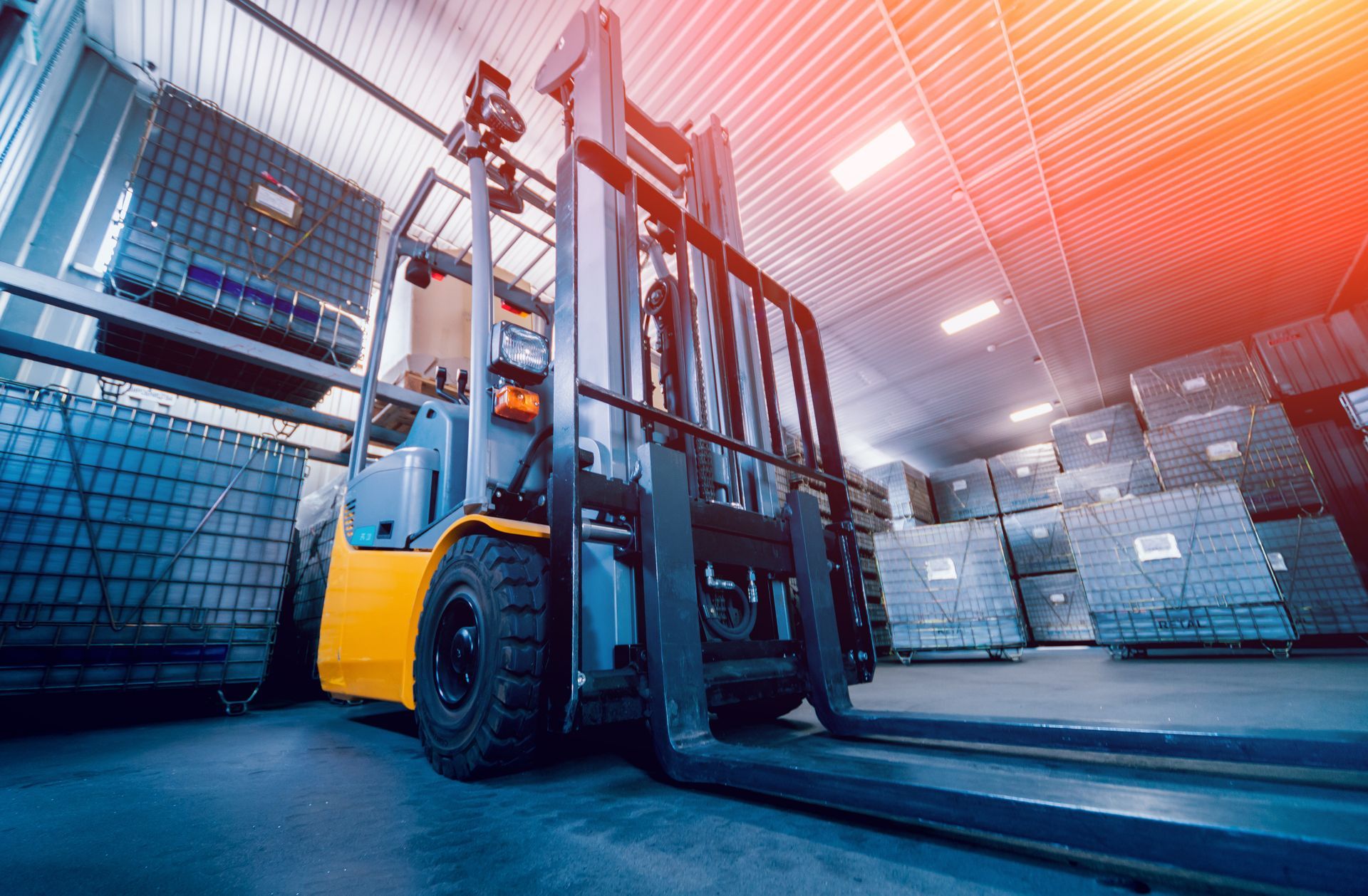 Yellow forklift in a warehouse, loading goods onto shelves. Bright lighting and stacks of cargo visible.