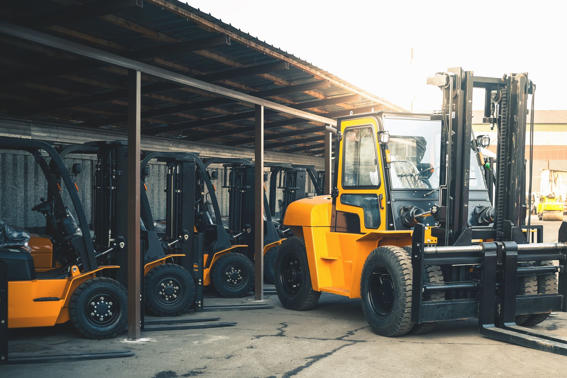 Yellow forklift in a row with other forklifts under a covered structure. Yellow forklift in a row with other forklifts under a covered structure.