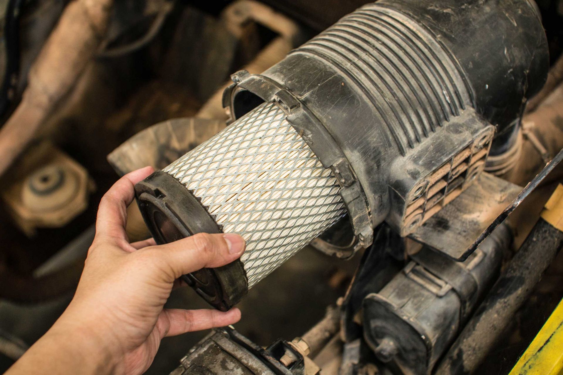 Hand removing an air filter from a vehicle's engine compartment. Hand removing an air filter from a vehicle's engine compartment.