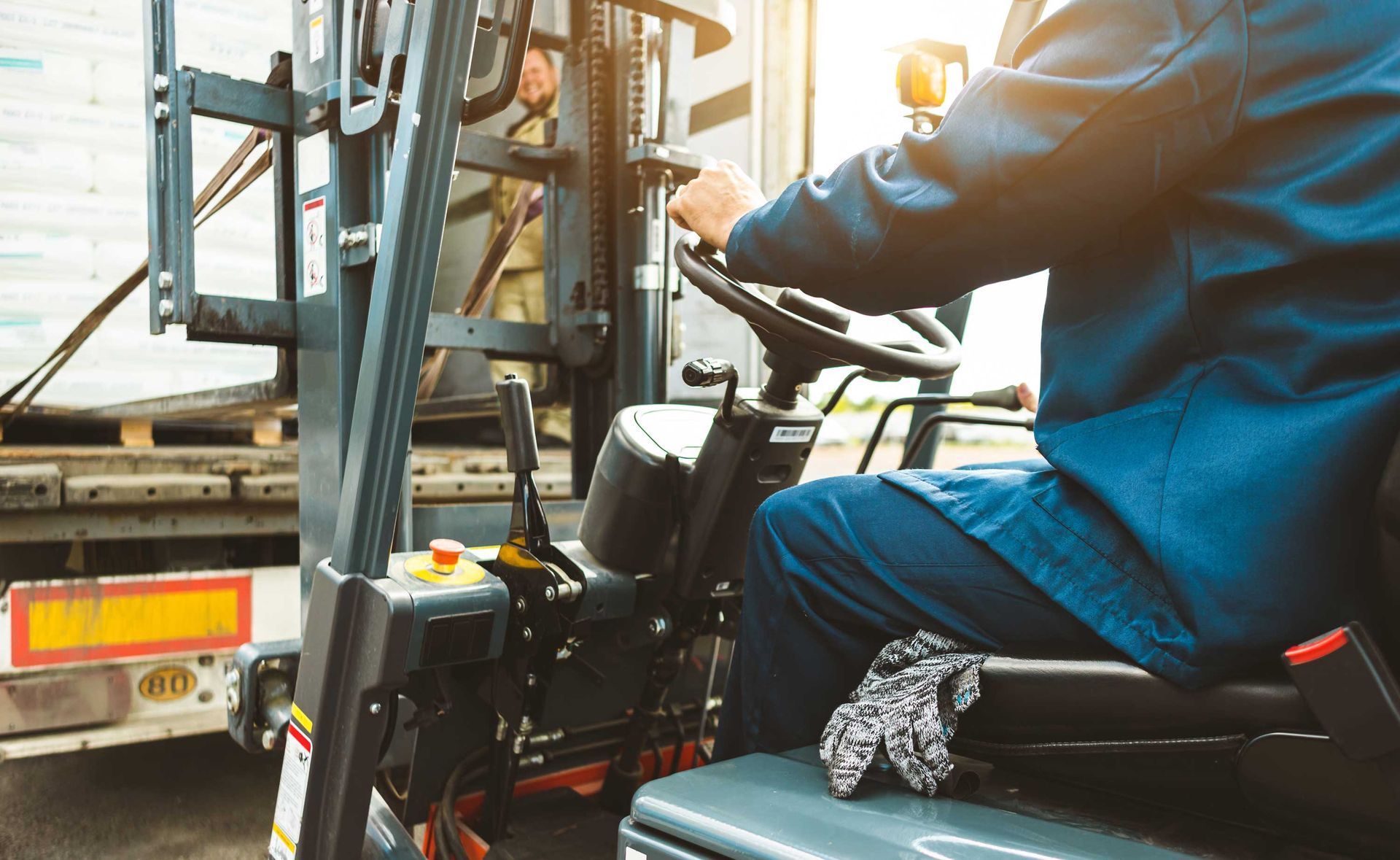 Worker operating a forklift to load materials onto a truck in a warehouse area. Worker operating a forklift to load materials onto a truck in a warehouse area.