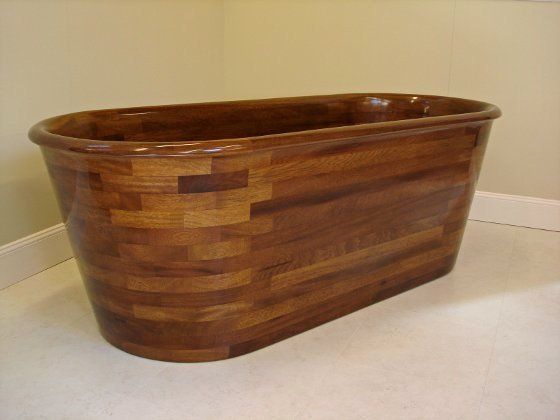 A wooden bathtub is sitting on the floor in a bathroom