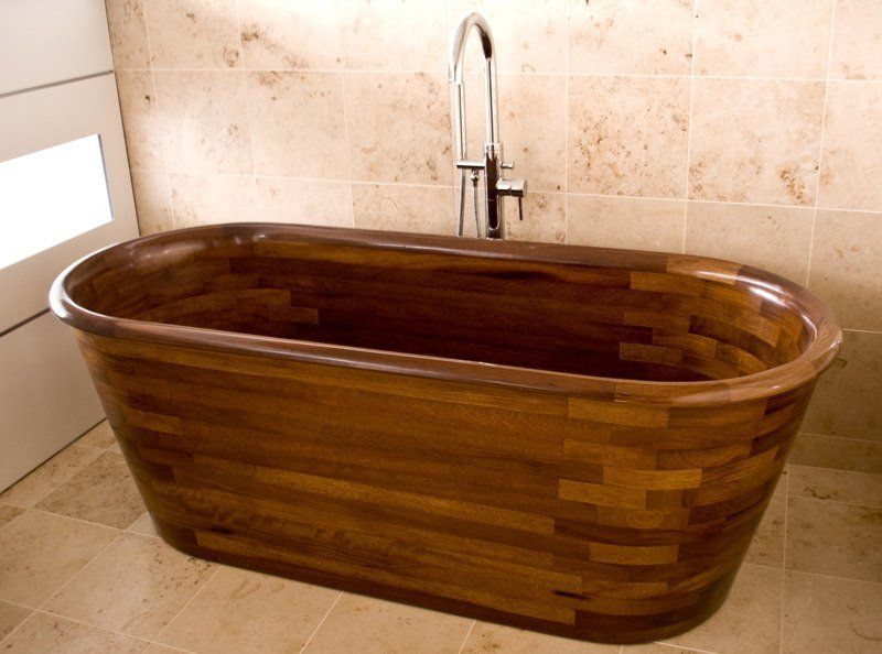 A wooden bathtub in a bathroom with a faucet