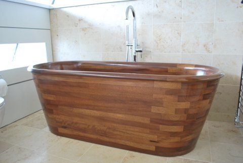 A wooden bathtub in a bathroom with a faucet