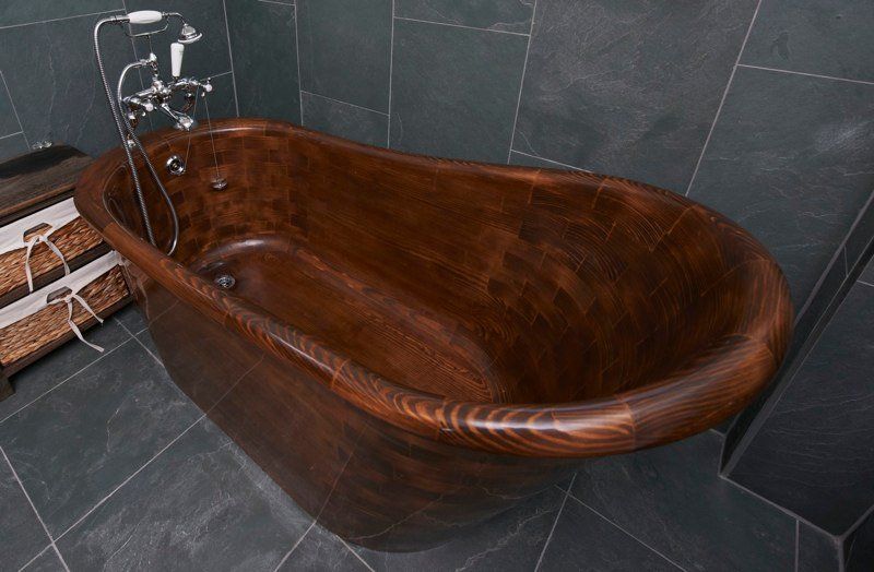 A wooden bathtub in a bathroom with a shower head