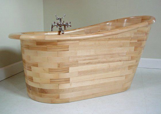 A wooden bathtub is sitting on the floor in a bathroom.