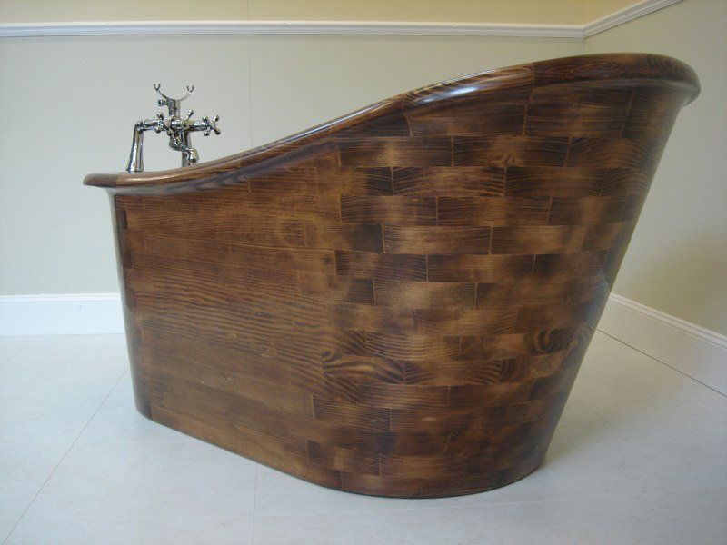 A wooden bathtub is sitting on a tiled floor in a bathroom.