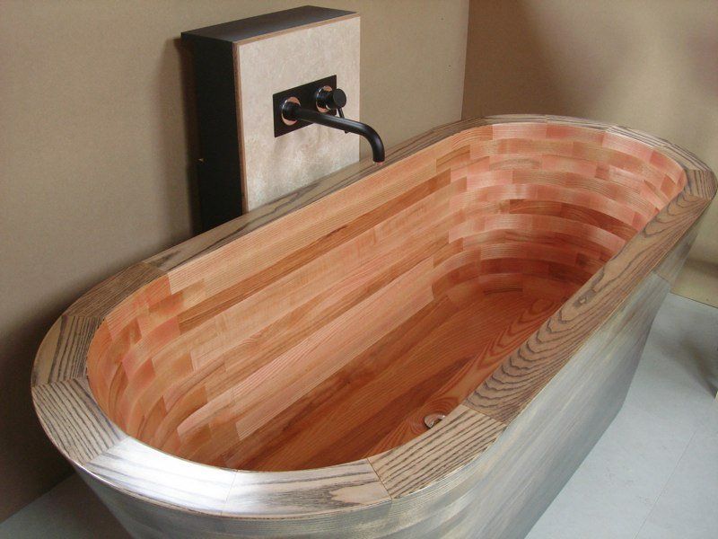 A wooden bathtub in a bathroom next to a faucet