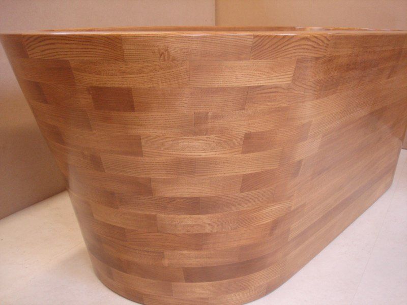 A wooden bathtub is sitting on top of a white table.
