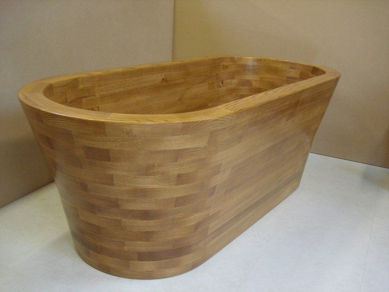 A wooden bathtub is sitting on a white surface.