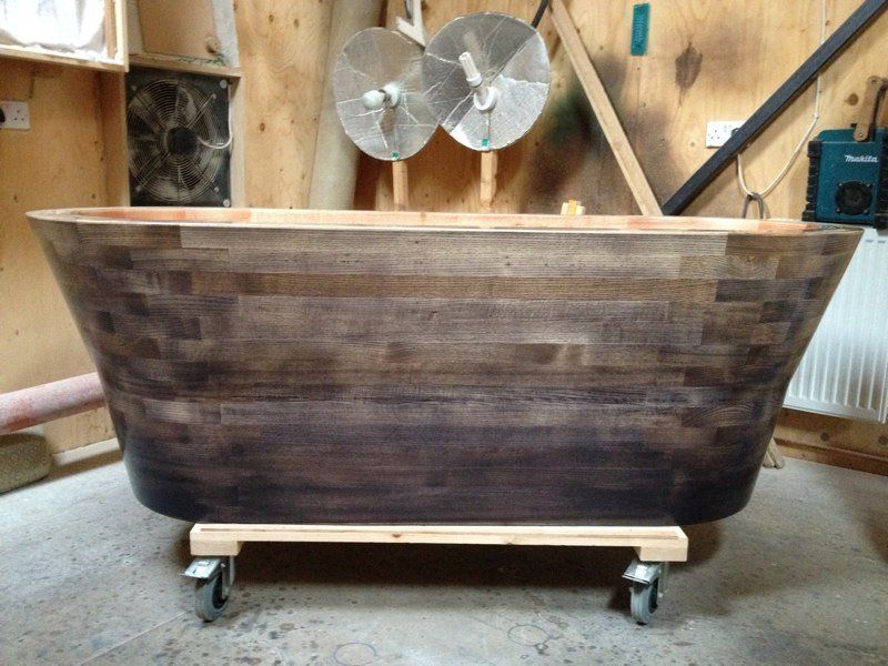 A wooden bathtub is sitting on wheels in a room