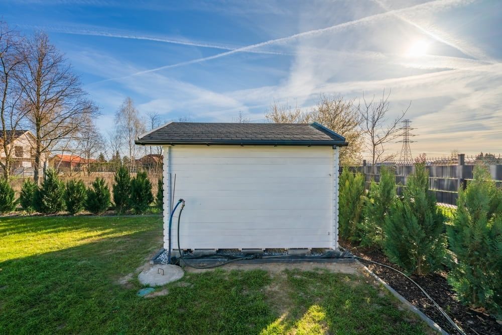 White Shed in a Grassy Yard, Surrounded by Shrubs — ShedBoss in Malanda, QLD