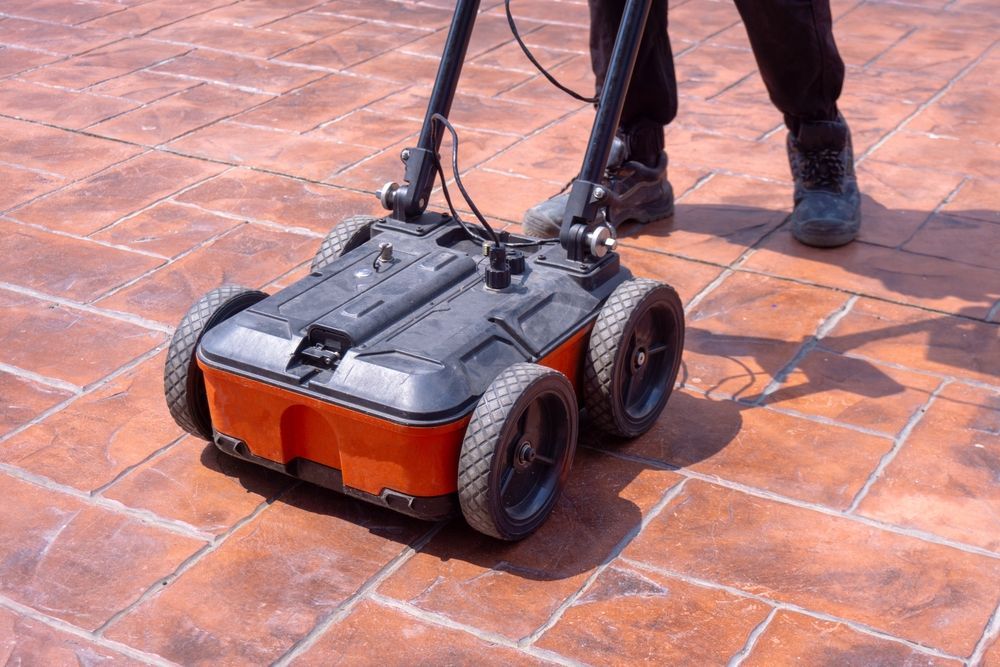 Person using a black and orange floor-cleaning machine on a tiled surface