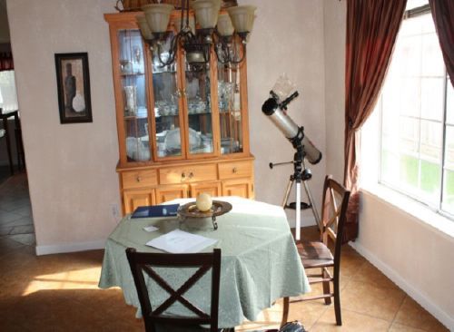 A dining room with a table and chairs and a telescope