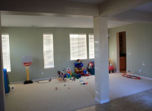 A room with a lot of toys on the floor and a basketball hoop.
