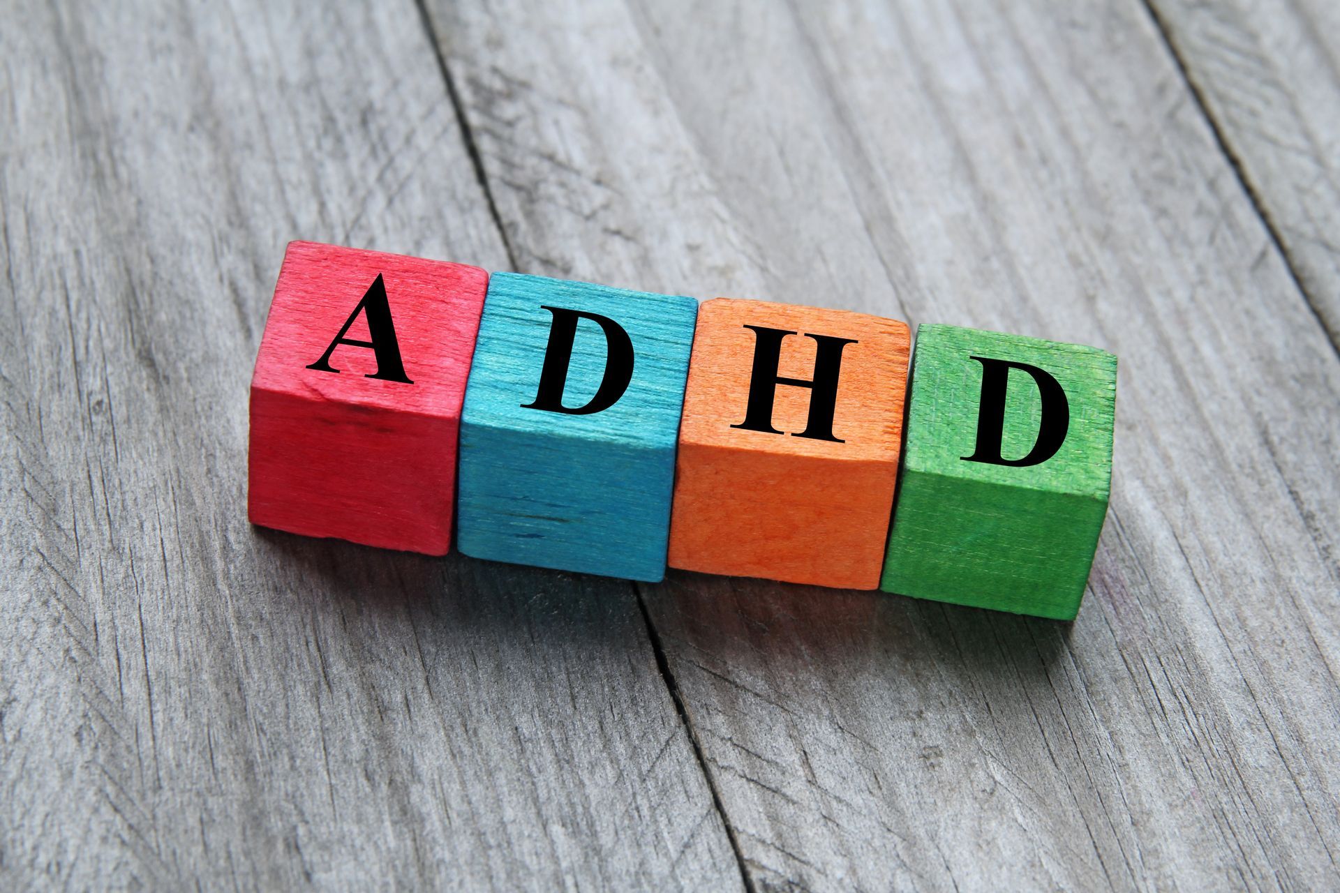 The word adhd is written on colorful wooden blocks on a wooden table.