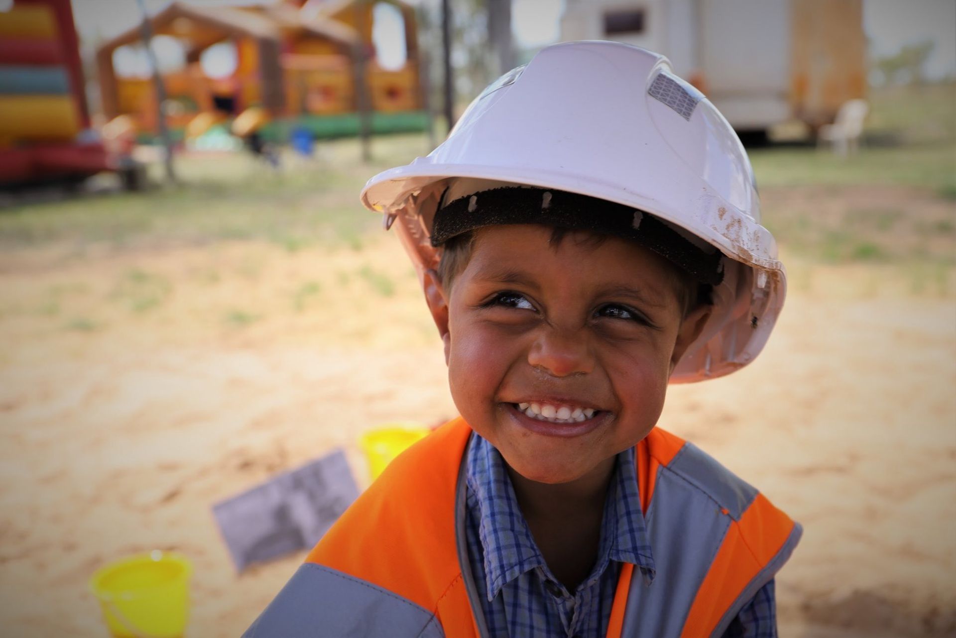 A young boy wearing a hard hat and smiling.