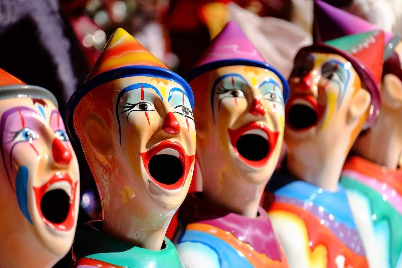 A group of clown figurines with their mouths open are lined up in a row.
