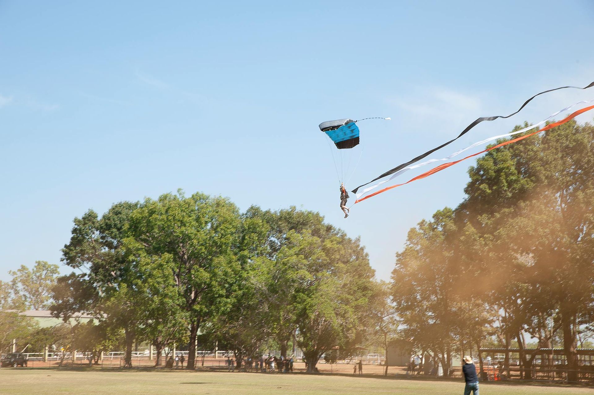 A man is flying a kite in a field with trees in the background.