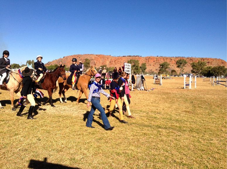 A group of people riding horses in a field
