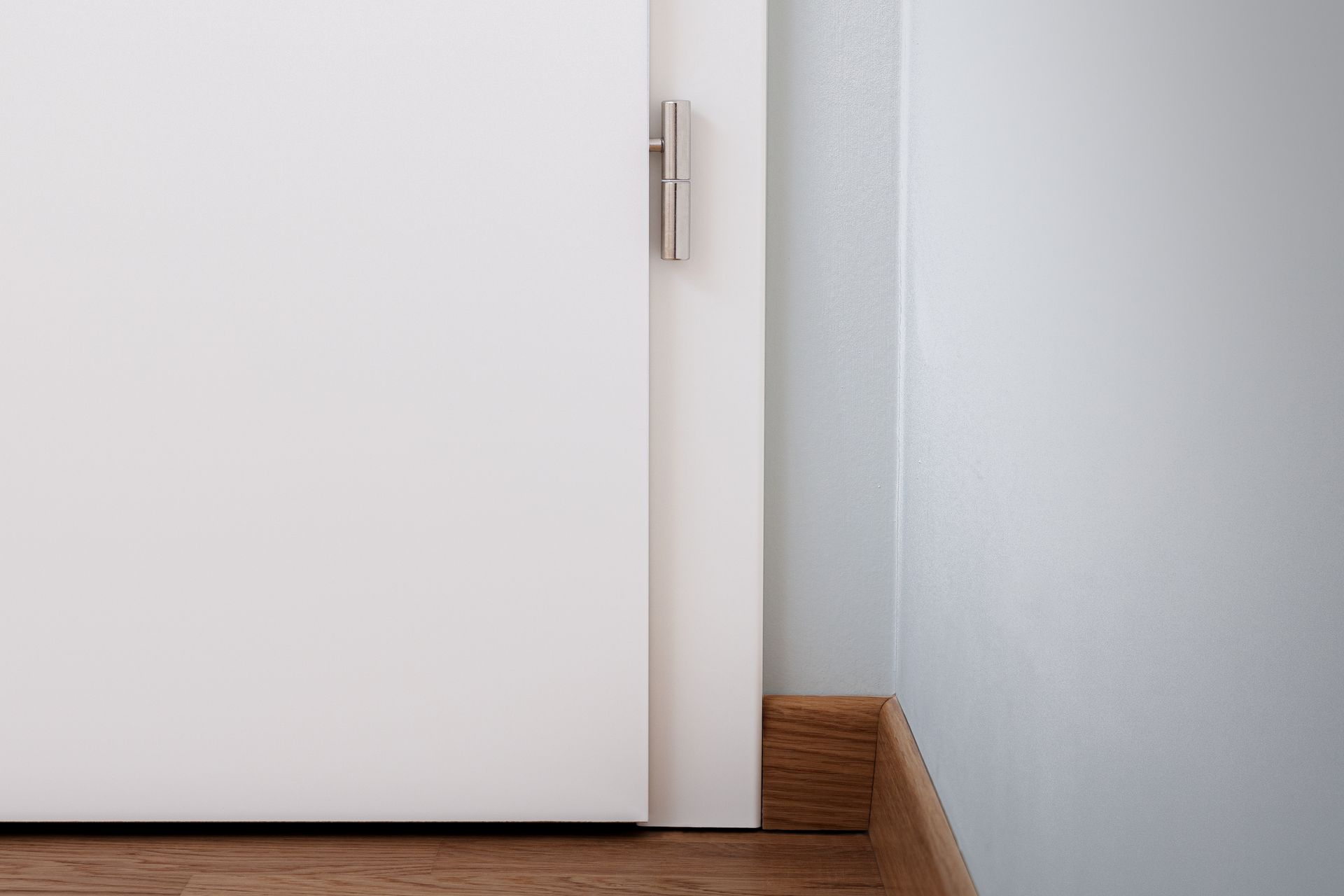 Une porte blanche est posée sur un parquet à côté d'un mur.