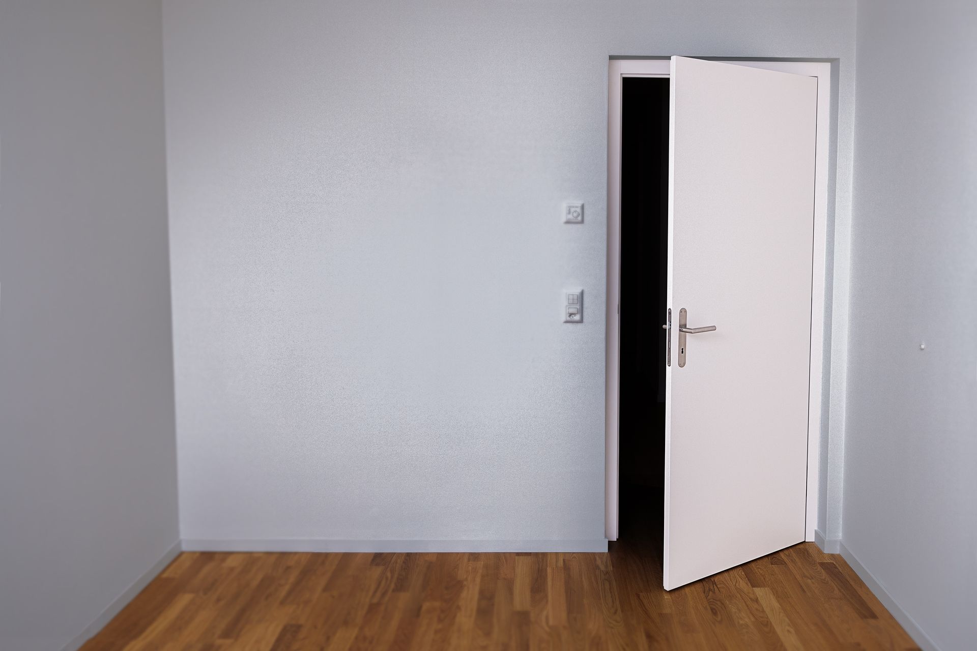 Une pièce vide avec un parquet et une porte ouverte.