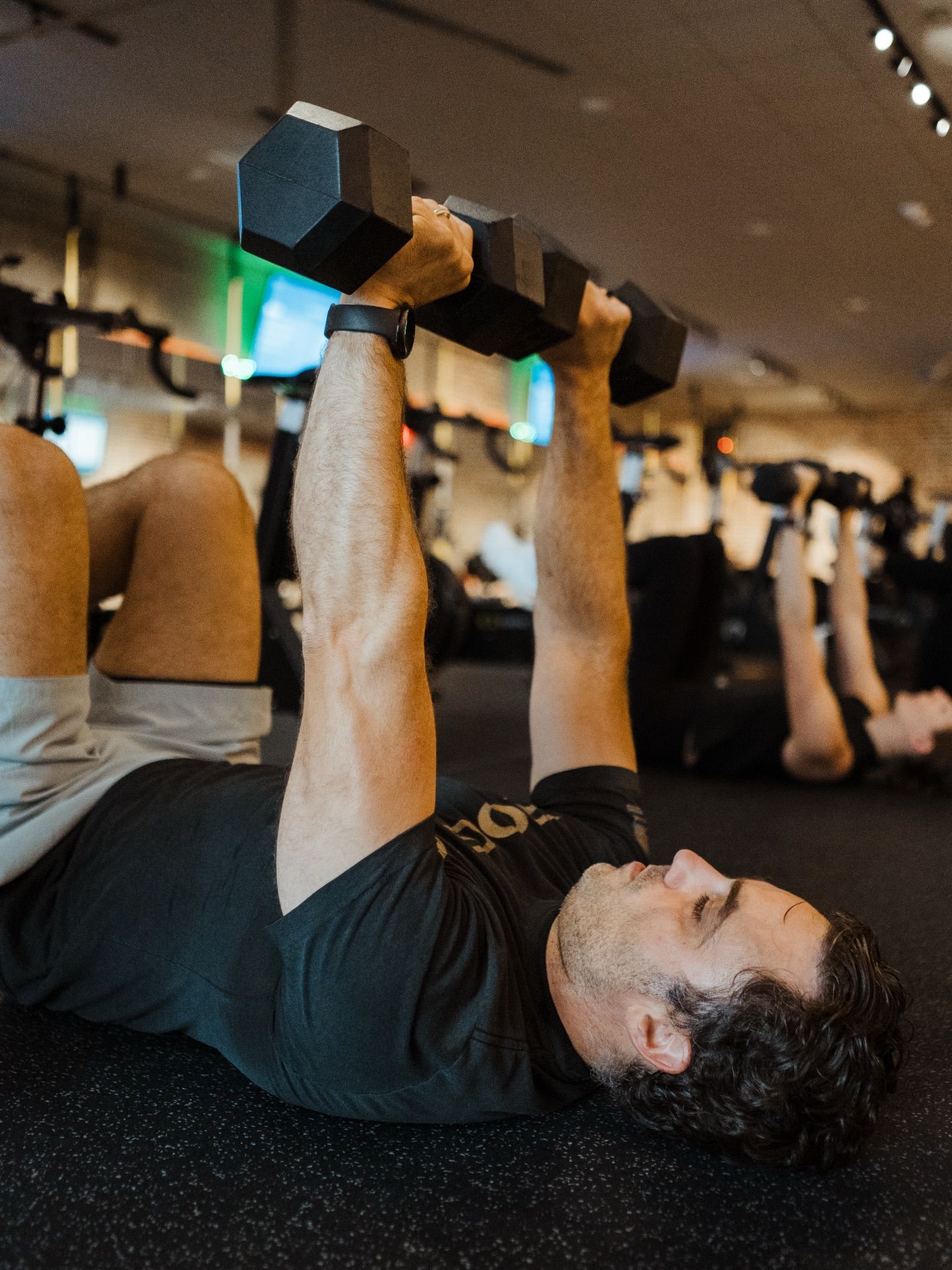 Two individuals face each other in a gym in New Orleans, one wearing a white tank top and the other a black t-shirt.