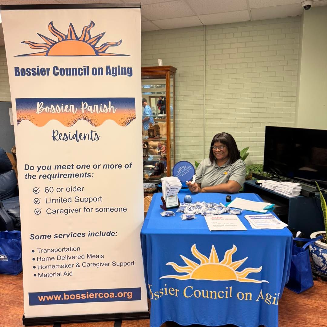 Woman at a Bossier Council on Aging booth with a blue tablecloth, banner, and service information.