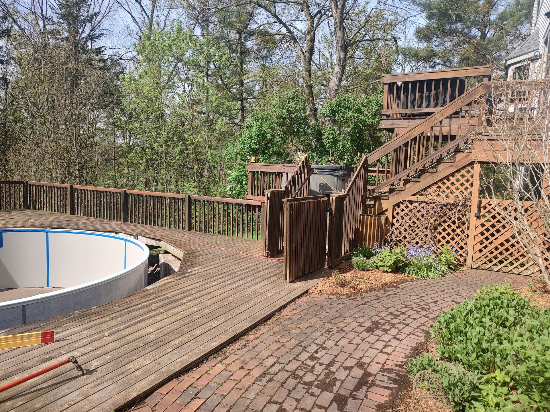 A wooden deck with stairs and a pool in the background.
