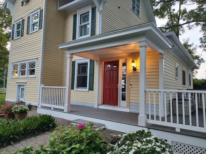 A yellow house with a red door and green shutters