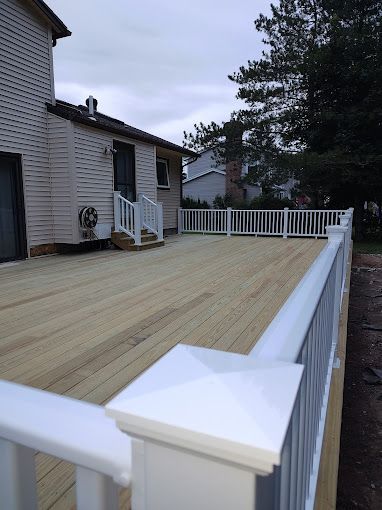A wooden deck with a white railing in front of a house.