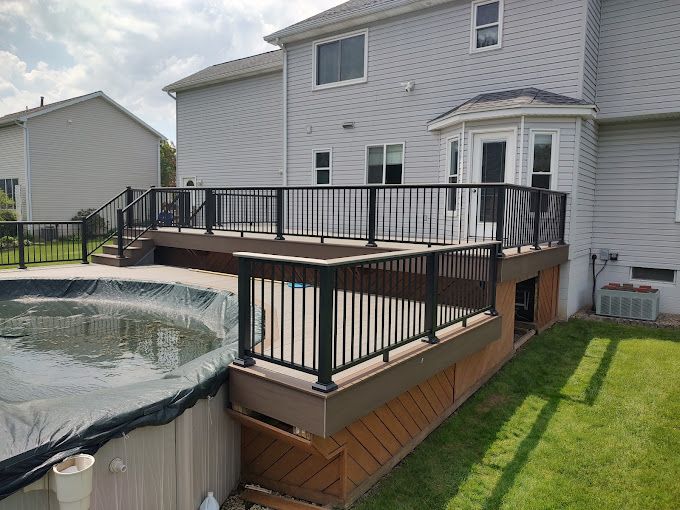 A large deck with a pool in the backyard of a house.