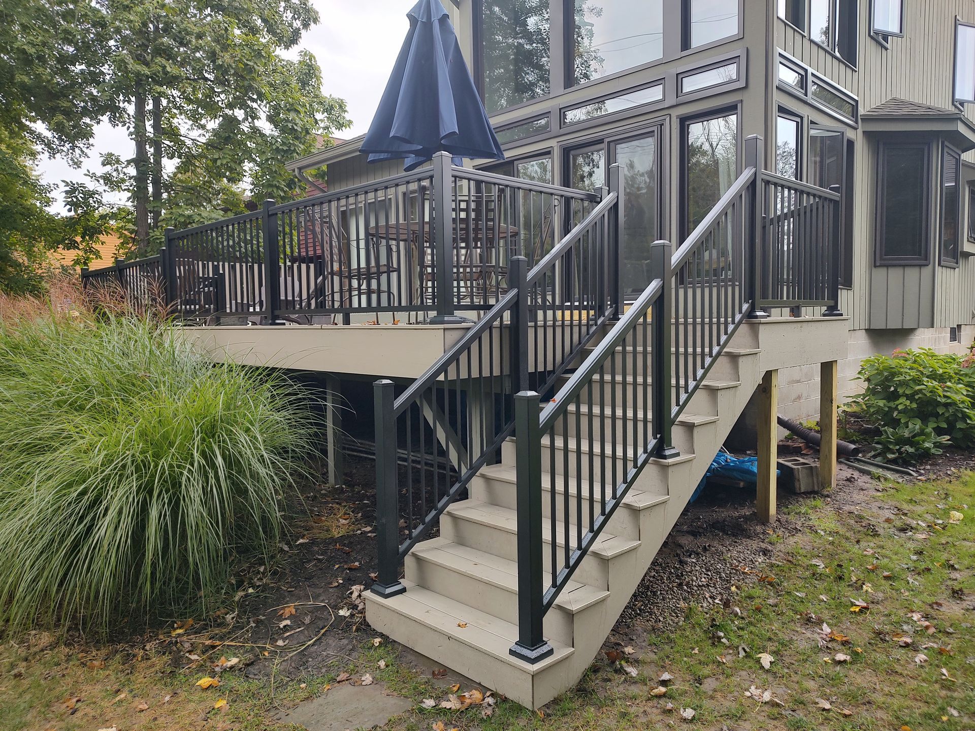 A deck with stairs leading up to it and a black railing.