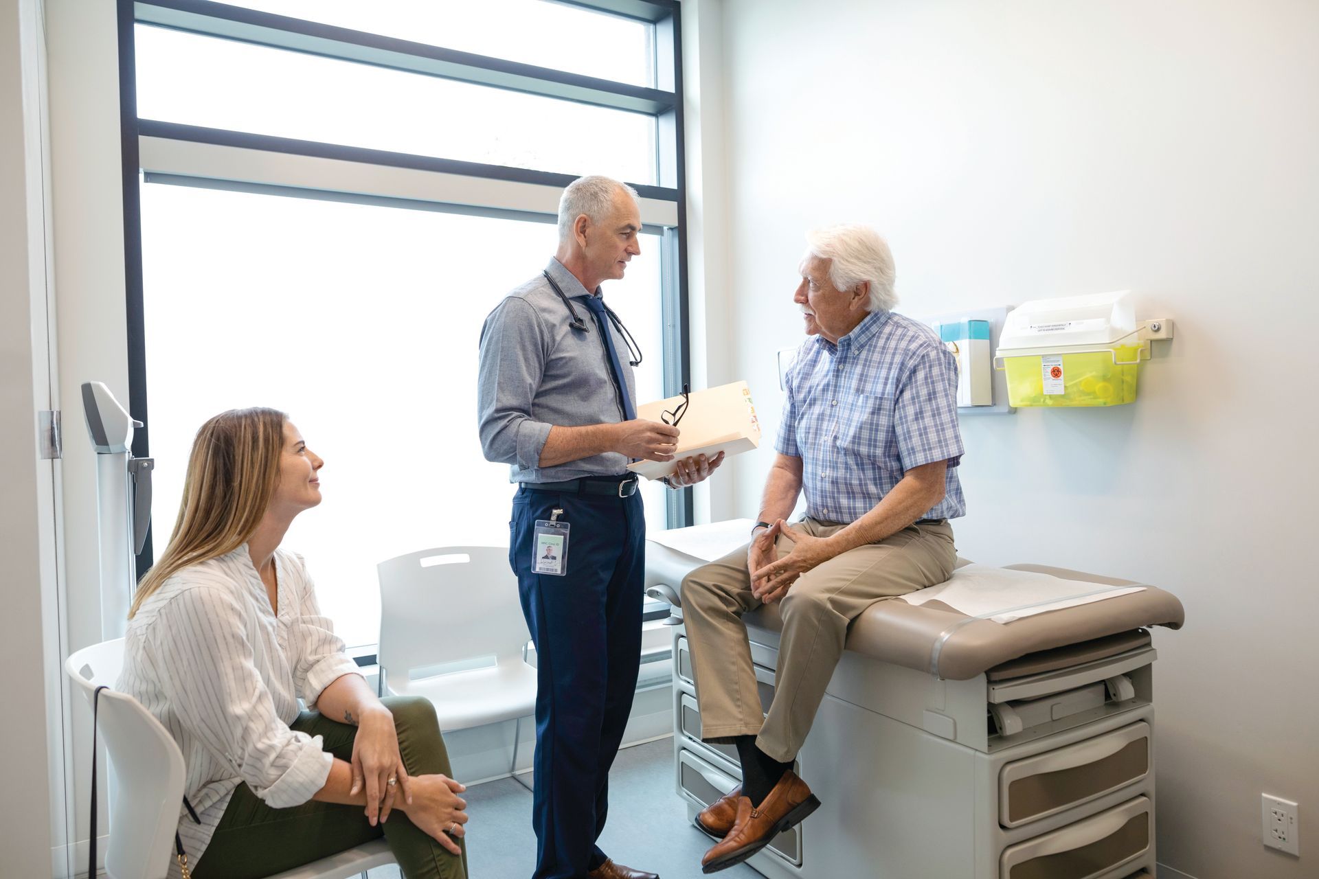 A doctor is talking to a patient while a woman sits in a chair. | You Health