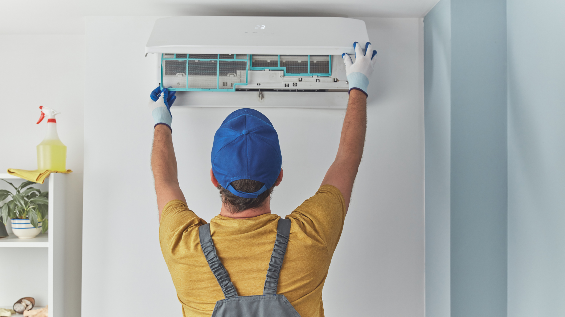 A man is cleaning an air conditioner in a room.