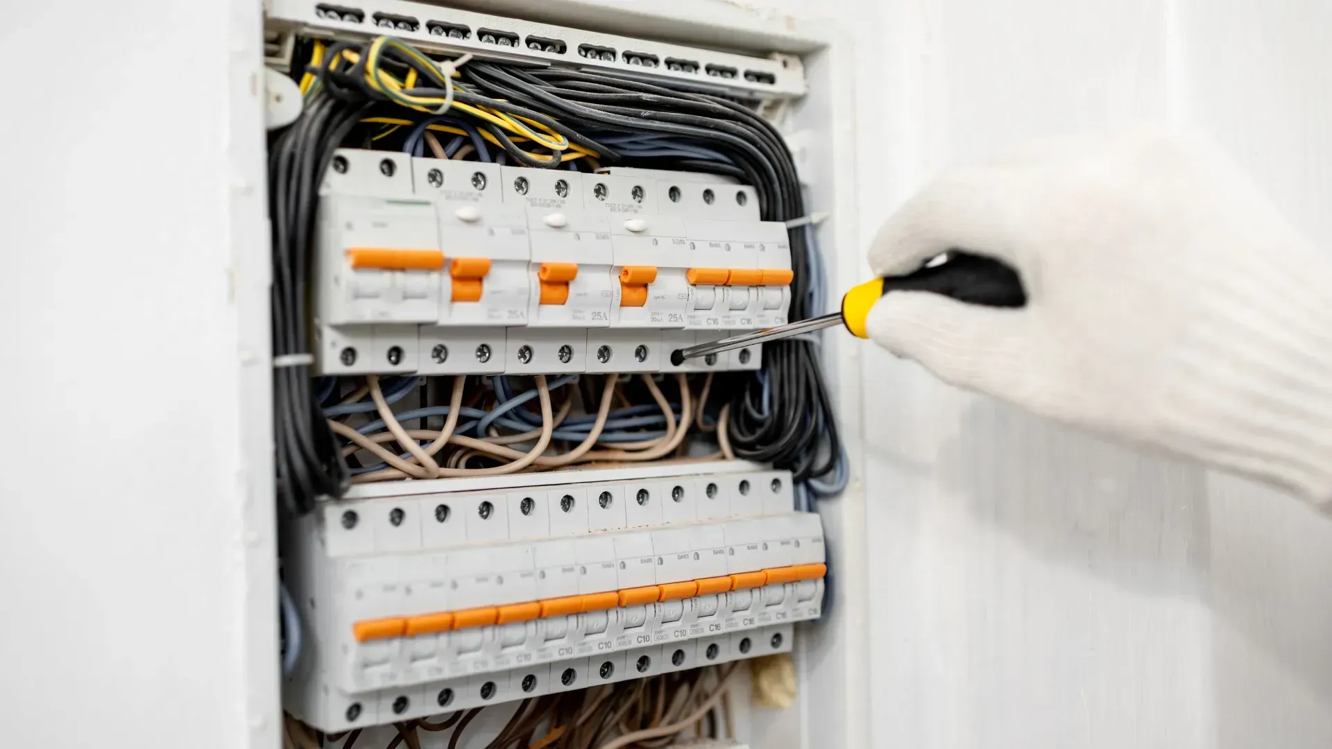 A person is working on an electrical box with a screwdriver.