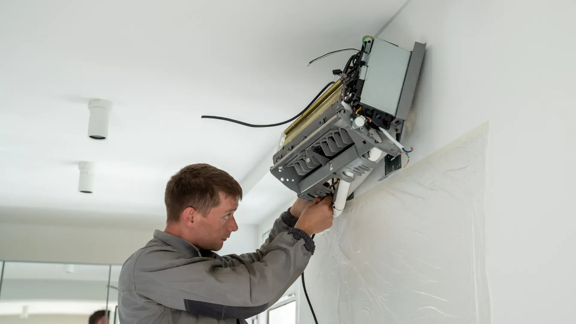 A man is installing an air conditioner on a wall.