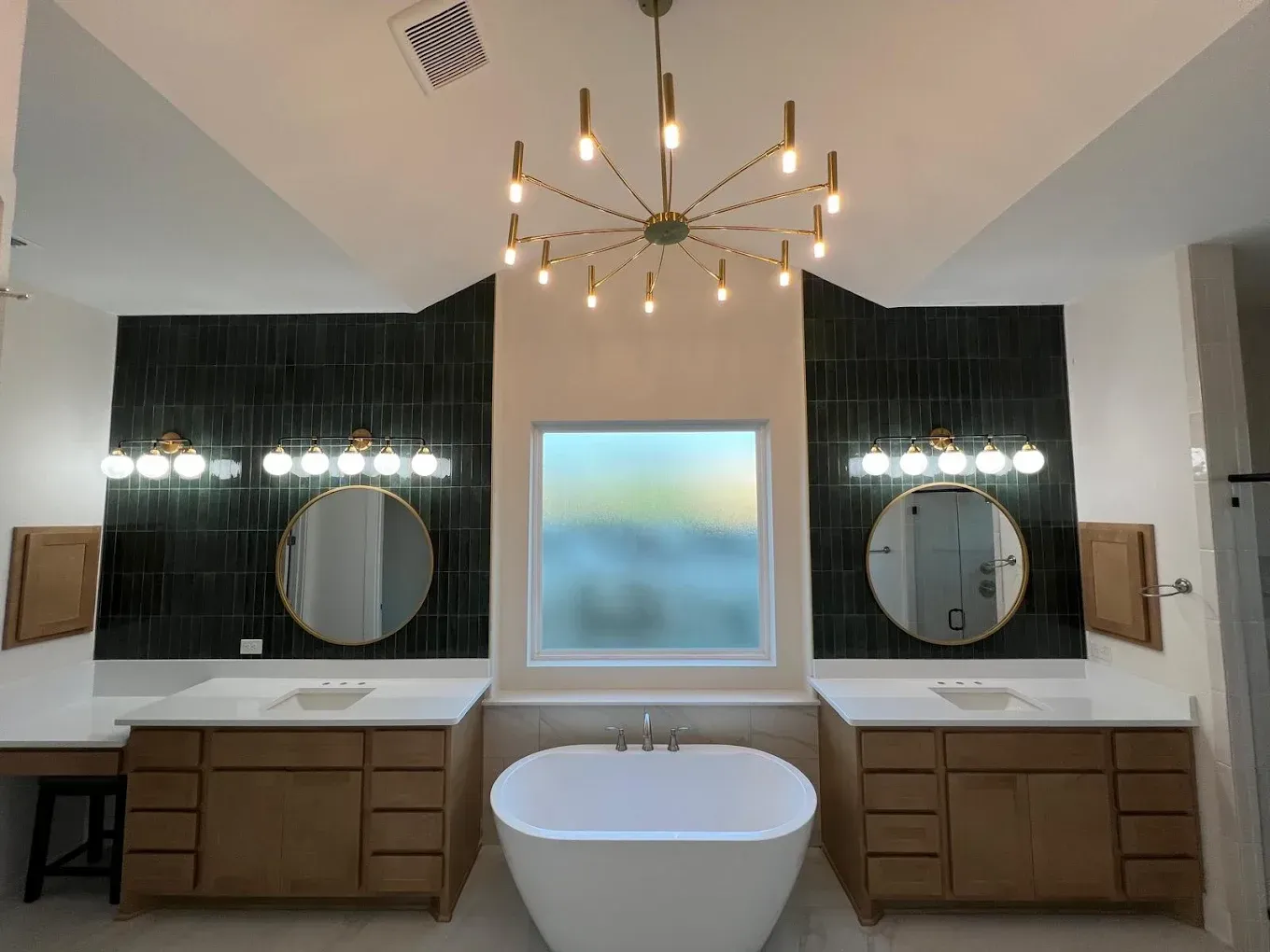 Modern bathroom with dual vanities, freestanding tub, and a decorative chandelier.
