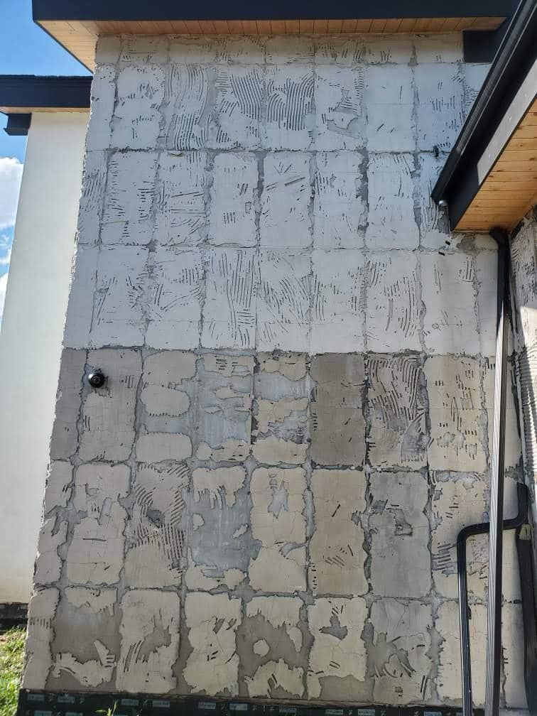 Exterior wall with removed tiles, showing underlying concrete squares.