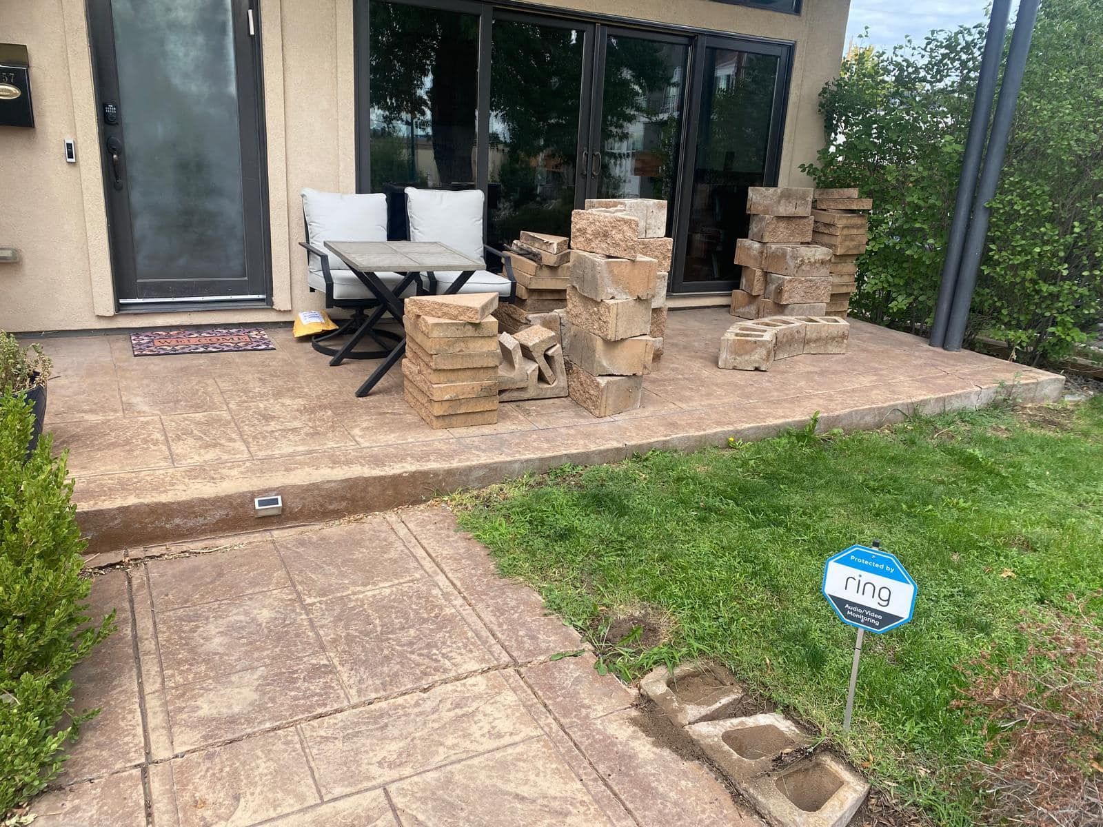 Front porch with stacked bricks, small table and chairs, and a walkway.