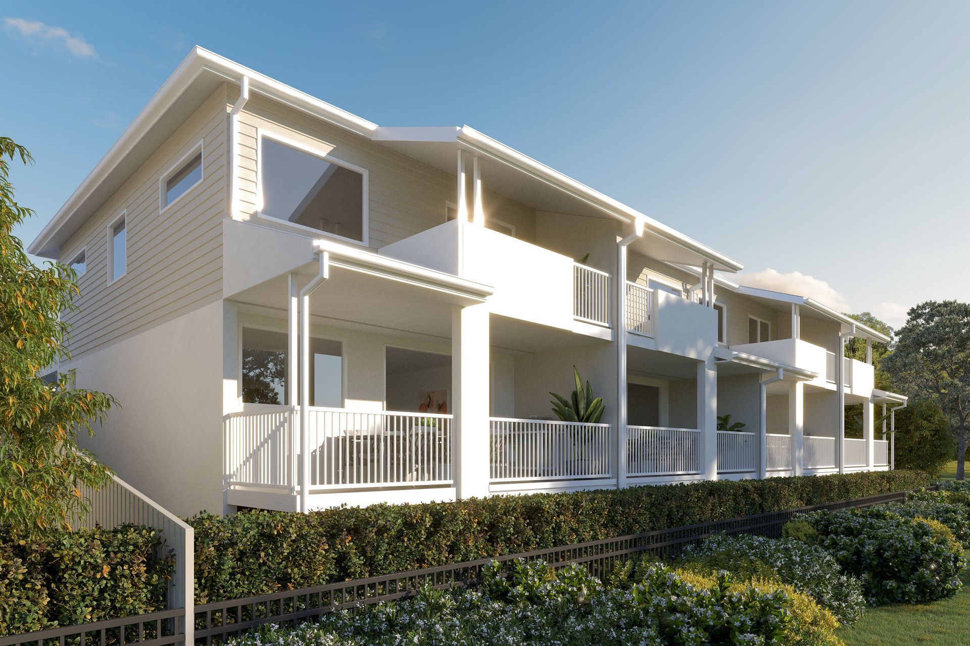 Row of modern townhouses with balconies, light beige siding, and white trim, set on a hillside.